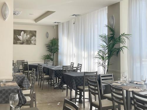 Hotel Little في ريميني: غرفة طعام بها طاولات وكراسي ونباتات