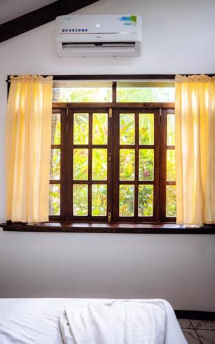 a window in a bedroom with yellow curtains and a bed at FLOR DE PARAISO BUNGALOWS in Montezuma
