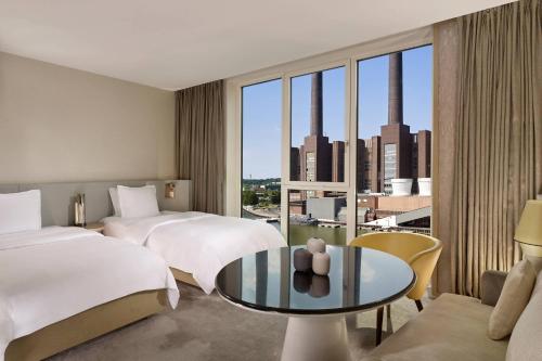 um quarto de hotel com duas camas e uma mesa de vidro em The Ritz-Carlton, Wolfsburg em Wolfsburg