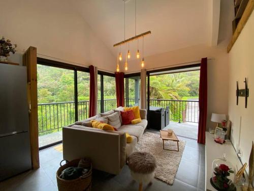 a living room with a couch and large windows at Le Cocon des Songes, reposez vous en pleine nature in La Plaine des Palmistes