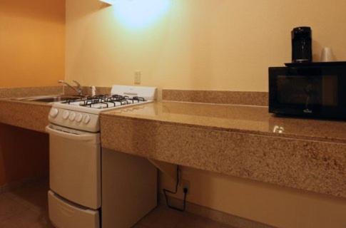 a kitchen counter with a stove and a microwave at Guest Inn San Benito/Harlingen in San Benito