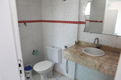 uma casa de banho com um WC, um lavatório e um espelho. em Hotel Pousada Oasis em Conde