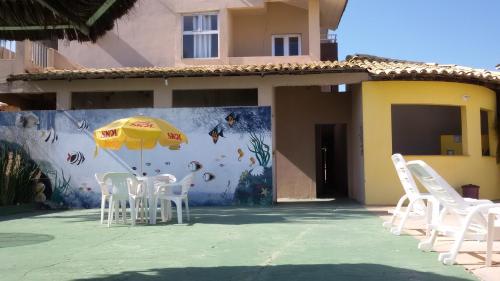 a wall with chairs and an umbrella in front of a house at Hotel Pousada Oasis in Conde