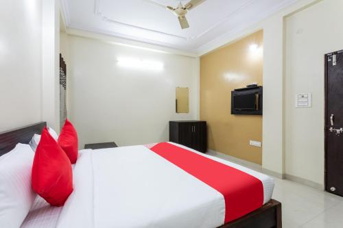 um quarto com uma cama branca e almofadas vermelhas em Flagship Om Gulmohar Avenue em Bhopal
