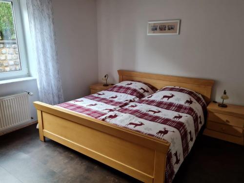 - une chambre dotée d'un lit avec une couverture rouge et blanche dans l'établissement FeWo-Am-Nationalpark-Eifel, à Nideggen
