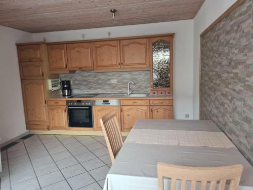 a kitchen with wooden cabinets and a table with chairs at FeWo-Am-Nationalpark-Eifel in Nideggen