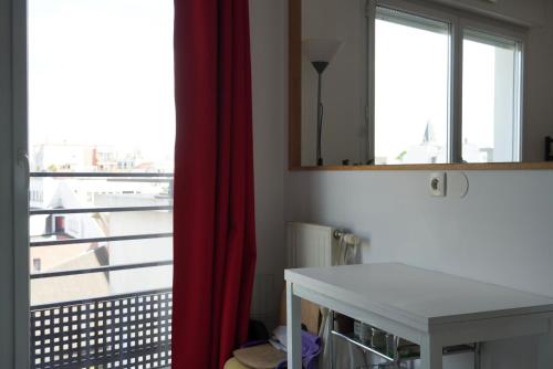 Cette chambre comprend un rideau rouge, une table et une fenêtre. dans l'établissement chambre privée POUR FEMME UNIQUEMENT dans appartement à partager - spatieux - 15 minutes Paris, à Saint-Denis