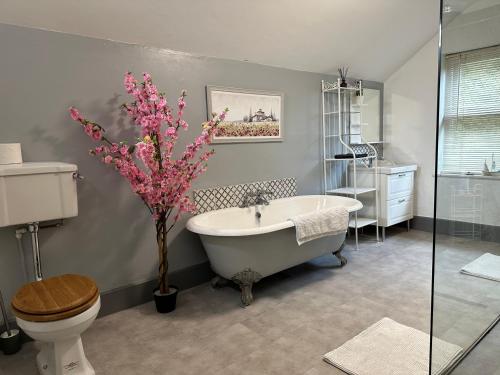 a bathroom with a tub and a toilet and a sink at The Hollies in South Kilworth