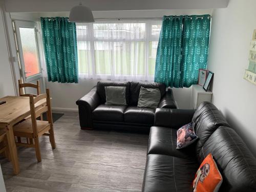 a living room with a black leather couch and a table at bulldog holidays 244 in Hemsby