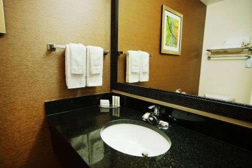 a bathroom with a sink and a mirror and towels at Fairfield Inn and Suites by Marriott Bartlesville in Bartlesville