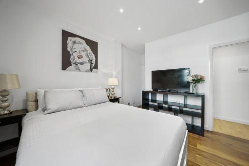 Schlafzimmer mit einem weißen Bett und einem Flachbild-TV in der Unterkunft Modern 2Bed Apartment London Cutty Sark O2 Arena Greenwich - Perfect for long stays in London