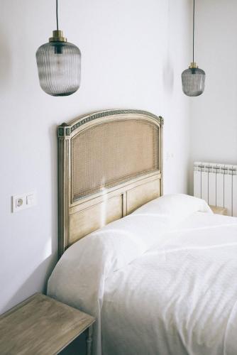a bedroom with a white bed and two pendant lights at Casa Montero in Viniegra de Abajo
