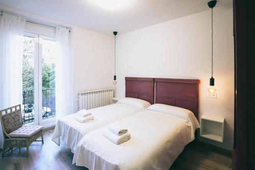 a bedroom with two beds and a chair and a window at Casa Montero in Viniegra de Abajo