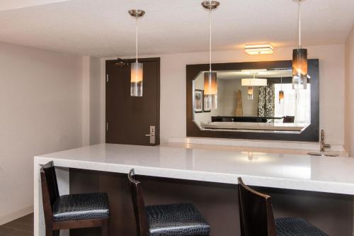 a kitchen with a bar with chairs and a mirror at Sheraton Minneapolis West Hotel in Minnetonka
