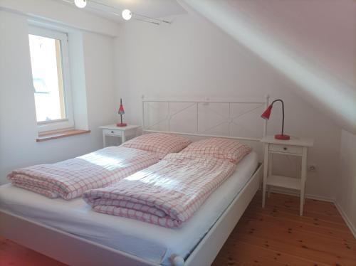 a white bedroom with a bed and a window at Stavenhof Röbel in Röbel