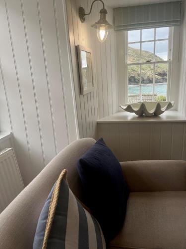a living room with a couch and a window at Lugger Hotel ‘A Bespoke Hotel’ in Portloe