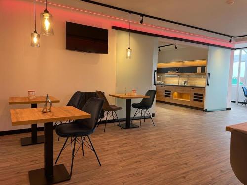 a room with tables and chairs and a kitchen at Meerzeit Strandhotel in Neuharlingersiel