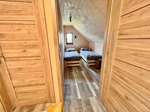 Apartament na Ogrodowej في تسيساكز: ممر به سريرين في غرفة بجدران خشبية