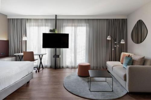 a living room with a bed and a couch and a tv at Residence Inn by Marriott Munich City East in Munich