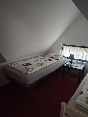 a bedroom with a bed and a table with a lamp at Lucerna in Hřensko