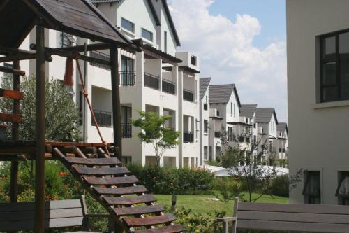 a row of white apartment buildings with benches in front at Classy and cosy Apt - Dainfern in Fourways