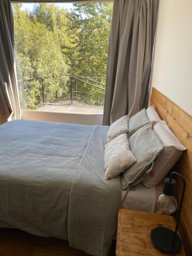 Cama en habitación con ventana grande en La casita de cami en San Carlos de Bariloche