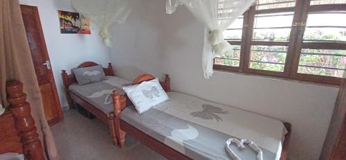 una piccola camera con due letti e una finestra di Villa Sunshine House ZANZIBAR a Jambiani