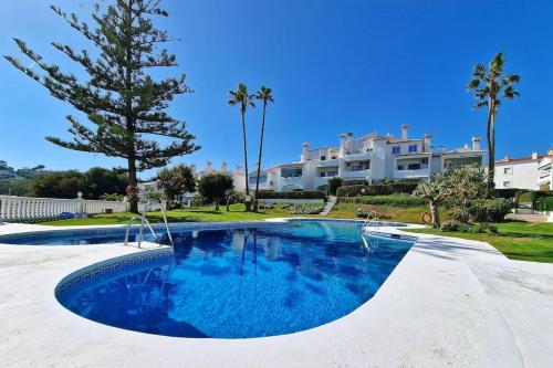 a swimming pool in front of a villa at Hermoso Piso en La Cala de Mijas con vistas al mar in La Cala de Mijas