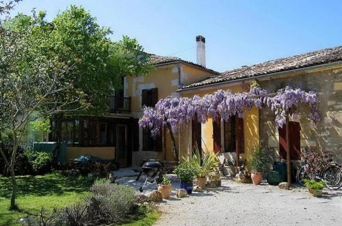 una casa con un montón de flores púrpuras colgando de ella en LA SOURCE, en Gémozac