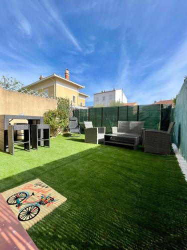 une cour avec une pelouse, des chaises et une table dans l'établissement Studio Moana avec parking et jardin, à La Londe-les-Maures