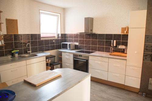 a kitchen with white cabinets and a sink and a microwave at Ferienwohnung in Celle in Celle