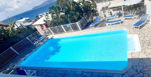 una grande piscina blu con sedie e l'oceano di Chambre Antillaise a Les Trois-Îlets