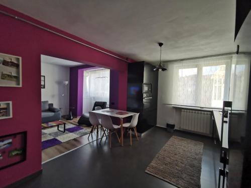 uma sala de estar com paredes roxas e uma mesa e cadeiras em Apartament ASR em Piatra Neamţ
