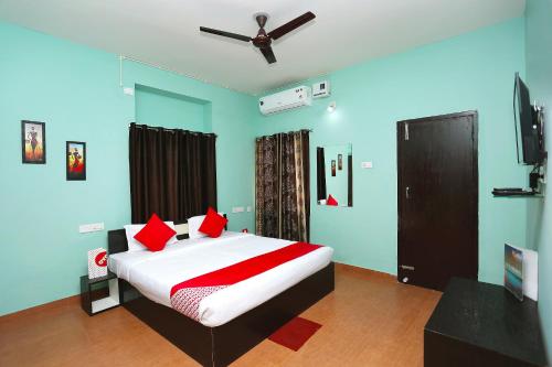 a bedroom with a bed with red pillows and a ceiling fan at Flagship The Maple Tree Hotels in Bhubaneshwar