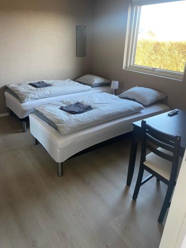 two beds in a room with a table and a window at Mejrup Bed and Breakfast in Holstebro