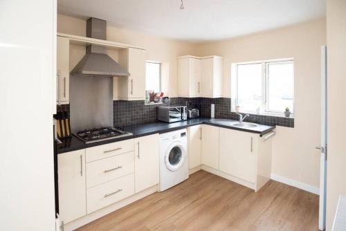 a kitchen with white cabinets and a washing machine at Sherwood Pines - Big Garden! in Clipstone