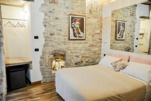 a bedroom with a stone wall with a bed and a fireplace at Case Brizi Assisi in Assisi