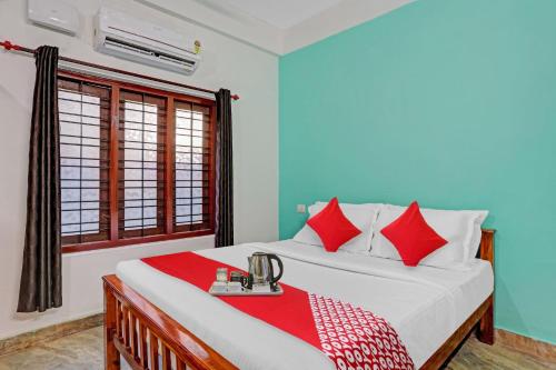 a bedroom with a bed with red and white pillows at Hotel O Bevis in Trivandrum