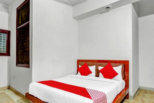 1 cama blanca con almohadas rojas en una habitación en OYO Yash Hotel, en Ghaziabad