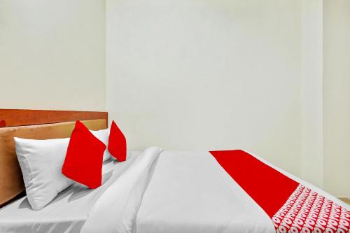 Una cama con almohadas rojas y blancas. en OYO Yash Hotel, en Ghaziabad