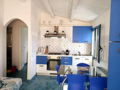 een keuken met blauwe kasten en een glazen tafel bij Casa dei Fiori in Donnalucata