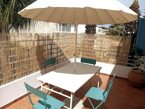 een tafel en stoelen met een parasol op een patio bij Casa dei Fiori in Donnalucata