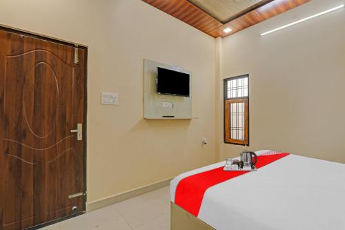 坎普爾的住宿－Flagship Sai Galaxy Hotel & Restaurant，卧室配有一张床,墙上配有电视。