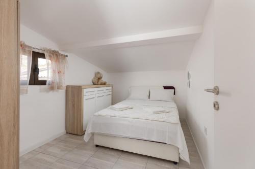 a white bedroom with a bed and a bathroom at Apartment Aleksic in Kotor