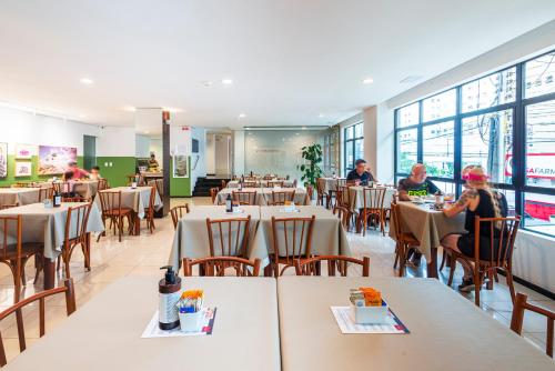 a restaurant with tables and people sitting at tables at Hotel Melo in Balneário Camboriú