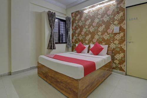 a bedroom with a large bed with red pillows at Flagship Sai Executive Lodging Near Fun Time Multiplex in Pune