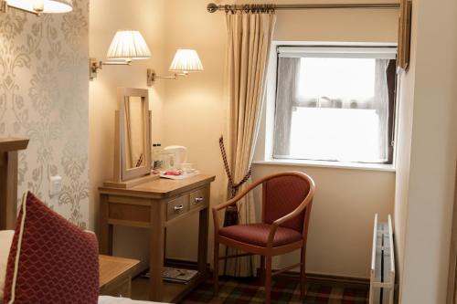 a room with a chair and a desk and a window at Oranmore in Ballymena