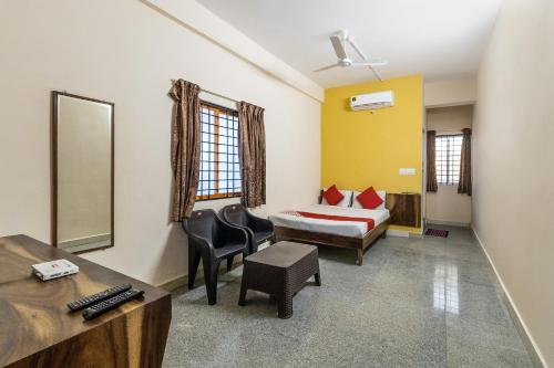 a hotel room with a bed and a desk and chair at OYO Supriya Lodge in Hassan