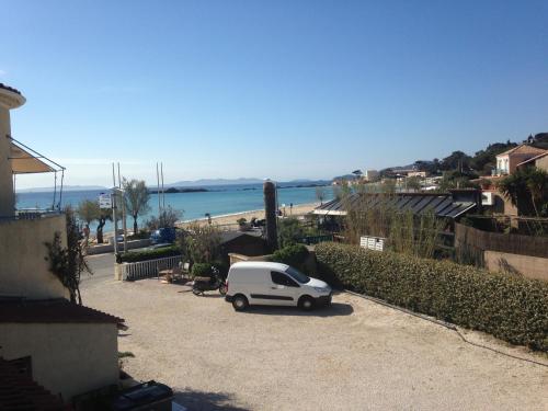 a small white car parked next to a beach at Hôtel Méditerranée in Le Lavandou