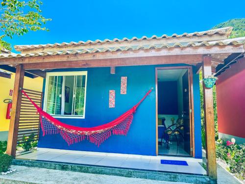 a house with a red hammock on the side of it at Pousada Sítio da Floresta in Sana